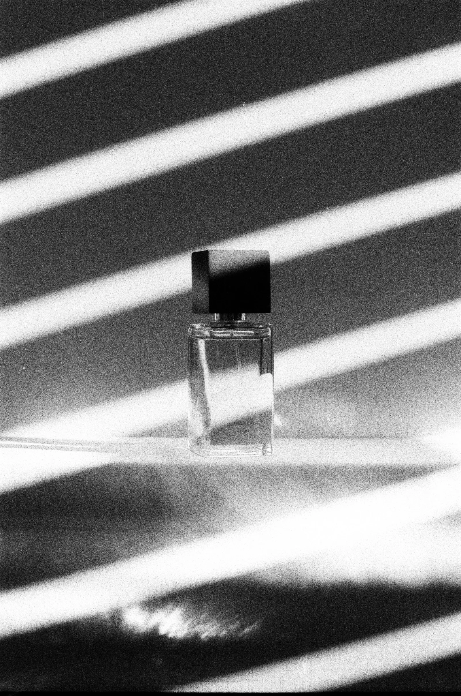 Black perfume bottle with long window shadows
